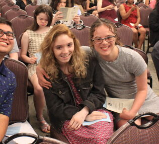 A group of students sitting in chairs waiting for the program to start.