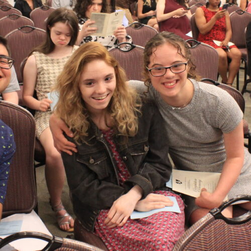 A group of students sitting in chairs waiting for the program to start.