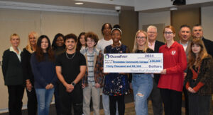 A group of men and women with one holding a large check.