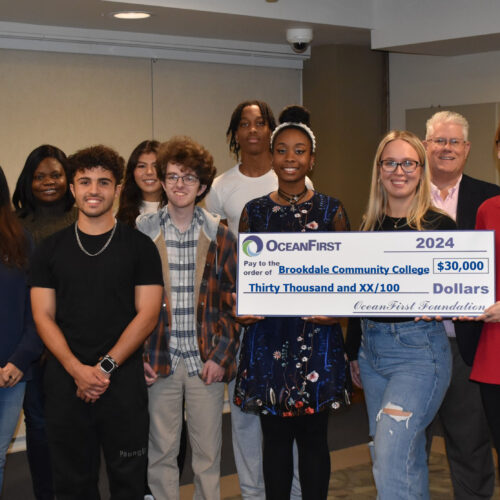 A group of men and women with one holding a large check.