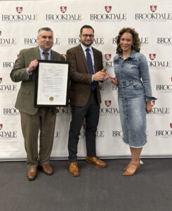 President Stout holding Crupi's resolution, outgoing Chairman Paul Crupi handing gavel to new Chairman Latonya Brennan.